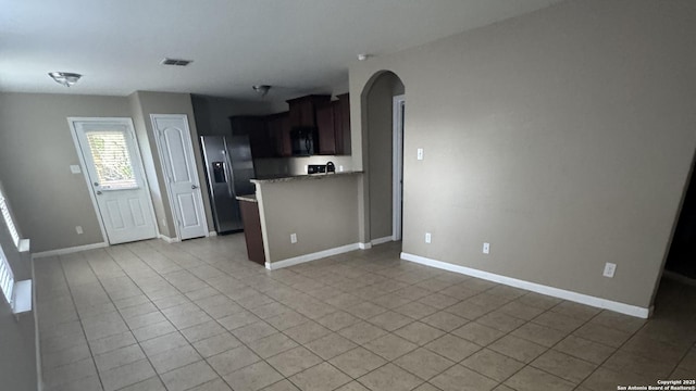 6322 Channel Vw, San Antonio, TX 78222 - kitchen with stainless steel refrigerator with ice dispenser, black microwave, arched walkways, light tile patterned flooring, and dark brown cabinets