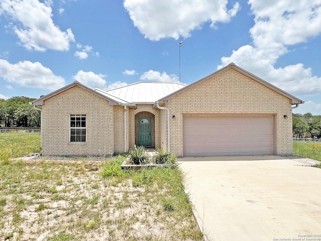 168 Great Oaks Blvd, La Vernia, TX 78121 - single story home with brick siding, an attached garage, driveway, a metal roof, and a standing seam roof
