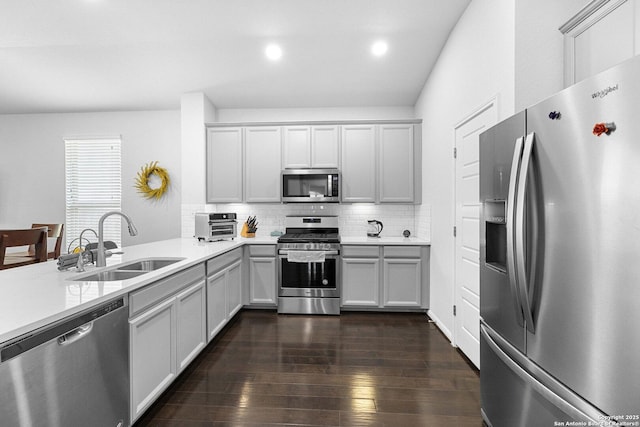 11631 Troubadour, San Antonio, TX 78245 - kitchen with appliances with stainless steel finishes, decorative backsplash, light countertops, dark wood-style flooring, and a peninsula
