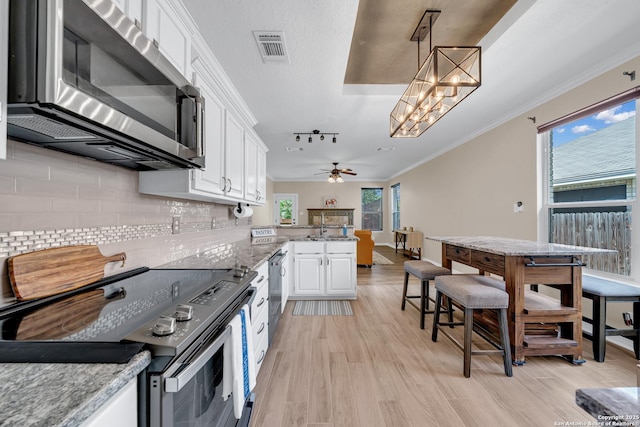 11546 Creek Bow, San Antonio, TX 78253 - kitchen with appliances with stainless steel finishes, a peninsula, white cabinets, tasteful backsplash, and ornamental molding
