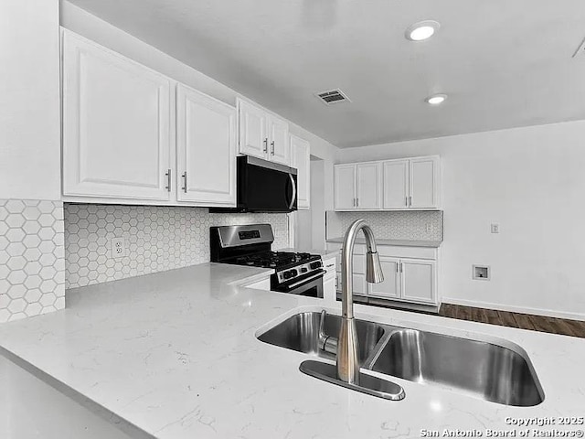 221 Peppergrass Cv, Kyle, TX 78640 - kitchen with stainless steel appliances, white cabinetry, light stone counters, decorative backsplash, and recessed lighting