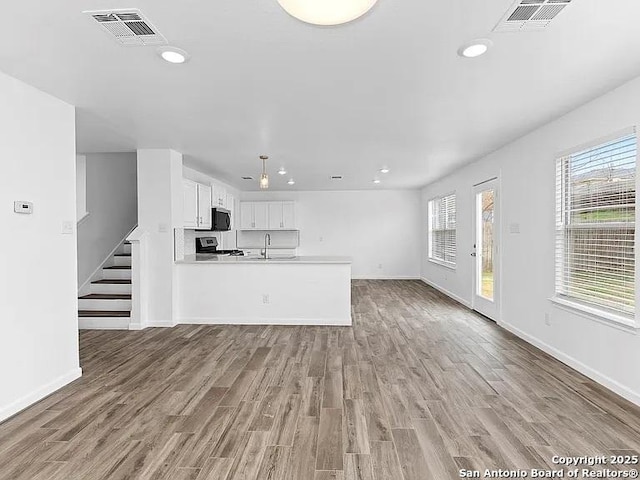 221 Peppergrass Cv, Kyle, TX 78640 - unfurnished living room with recessed lighting, wood finished floors, and stairs