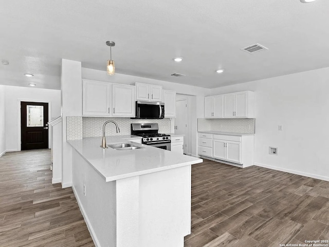 221 Peppergrass Cv, Kyle, TX 78640 - kitchen featuring stainless steel appliances, a peninsula, dark wood-style flooring, white cabinetry, and recessed lighting