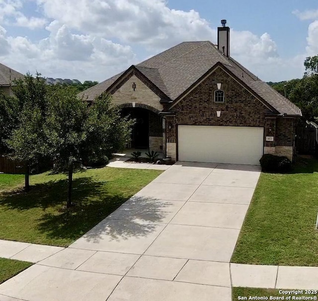 3822 Cordoba Crk, San Antonio, TX 78259 - french provincial home featuring concrete driveway, a front lawn, brick siding, a garage, and a chimney