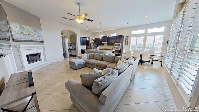 3822 Cordoba Crk, San Antonio, TX 78259 - living area featuring arched walkways, light tile patterned floors, ceiling fan, a high end fireplace, and recessed lighting