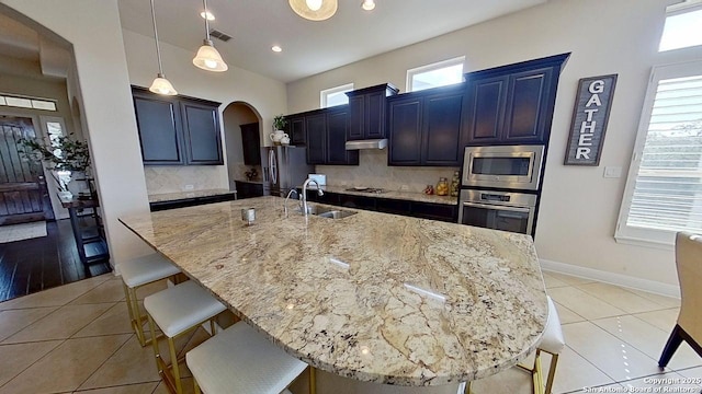 3822 Cordoba Crk, San Antonio, TX 78259 - kitchen with appliances with stainless steel finishes, a kitchen breakfast bar, arched walkways, light stone counters, and recessed lighting