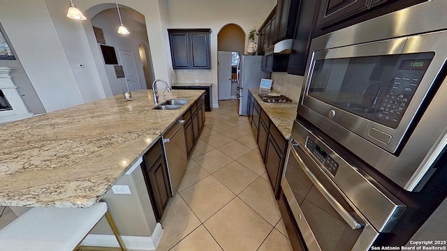 3822 Cordoba Crk, San Antonio, TX 78259 - kitchen featuring arched walkways, appliances with stainless steel finishes, light stone countertops, light tile patterned floors, and decorative light fixtures