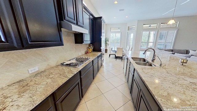3822 Cordoba Crk, San Antonio, TX 78259 - kitchen featuring stainless steel gas stovetop, under cabinet range hood, backsplash, light stone counters, and light tile patterned floors