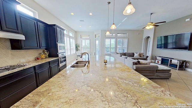 3822 Cordoba Crk, San Antonio, TX 78259 - kitchen featuring appliances with stainless steel finishes, arched walkways, open floor plan, light stone countertops, and backsplash
