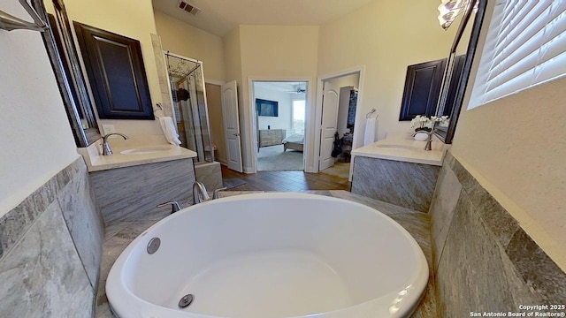 3822 Cordoba Crk, San Antonio, TX 78259 - ensuite bathroom featuring two vanities, a bath, tile walls, wood finished floors, and ceiling fan