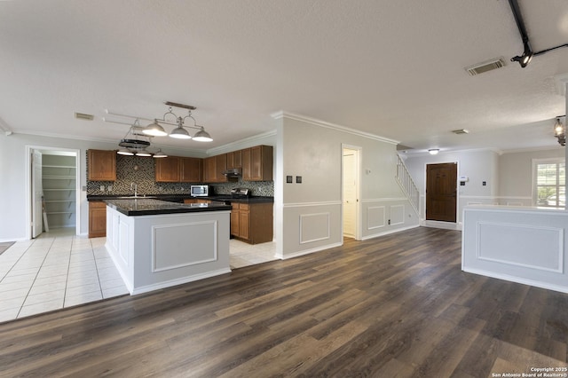 18510 Paloma Wood, San Antonio, TX 78259 - kitchen featuring rail lighting, dark countertops, ornamental molding, light wood-type flooring, and open floor plan