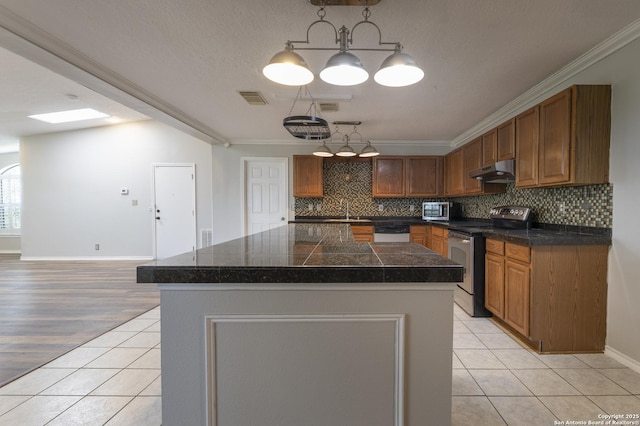 18510 Paloma Wood, San Antonio, TX 78259 - kitchen with appliances with stainless steel finishes, tile counters, under cabinet range hood, light tile patterned floors, and backsplash