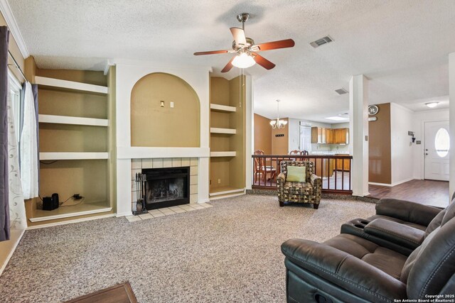 11063 Moonlit, San Antonio, TX 78249 - carpeted living room featuring a textured ceiling, built in shelves, ceiling fan, and a fireplace