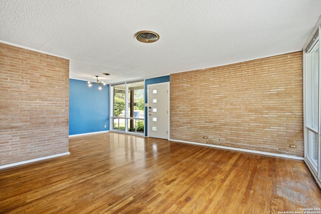 250 Maplewood, San Antonio, TX 78216 - unfurnished room featuring a textured ceiling, brick wall, and wood finished floors