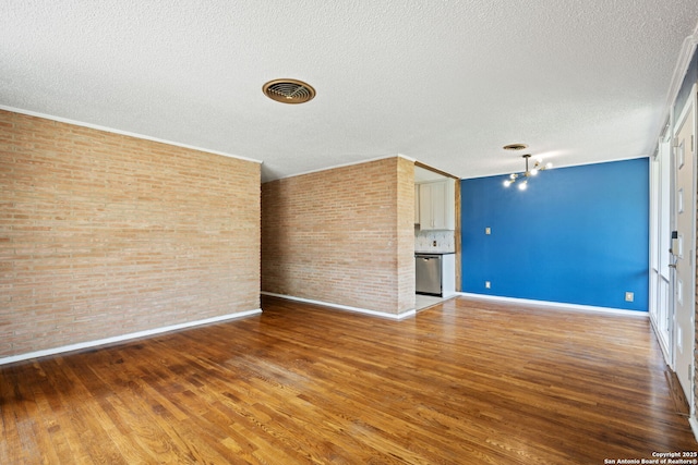 250 Maplewood, San Antonio, TX 78216 - unfurnished living room with a textured ceiling, wood finished floors, and brick wall