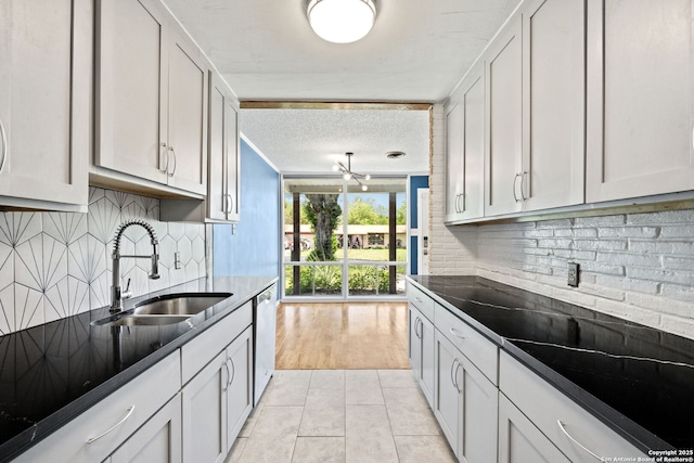 250 Maplewood, San Antonio, TX 78216 - kitchen with stainless steel dishwasher, light tile patterned flooring, tasteful backsplash, a textured ceiling, and dark countertops