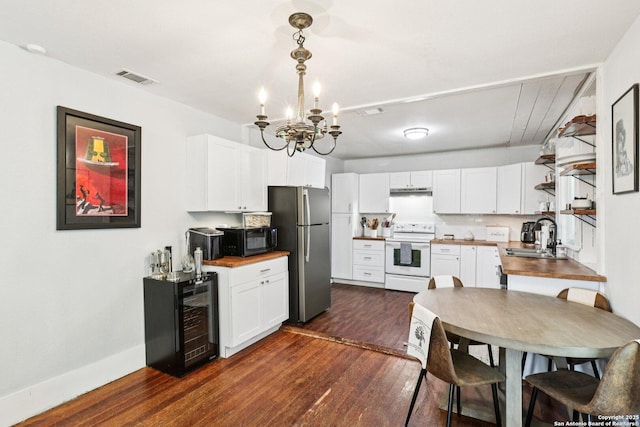 107 W Gilbert, Falls City, TX 78113 - kitchen with white electric stove, black microwave, freestanding refrigerator, beverage cooler, and a chandelier
