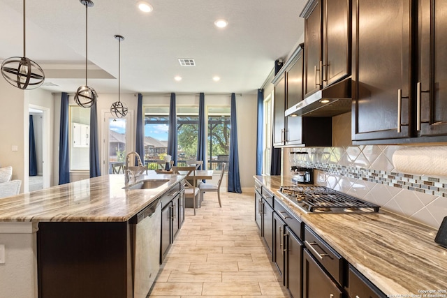 11910 Wilby, San Antonio, TX 78253 - kitchen with appliances with stainless steel finishes, under cabinet range hood, tasteful backsplash, a center island with sink, and dark brown cabinets