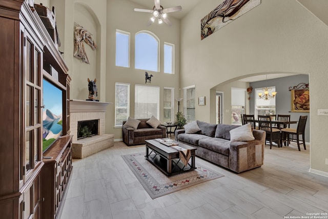 577 River Chase, New Braunfels, TX 78132 - living area featuring arched walkways, a high ceiling, a fireplace, a ceiling fan, and a chandelier