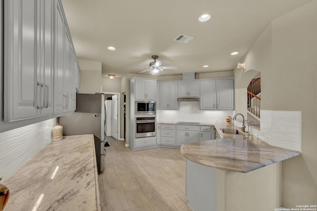 577 River Chase, New Braunfels, TX 78132 - kitchen featuring stainless steel appliances, a peninsula, decorative backsplash, light stone countertops, and a ceiling fan