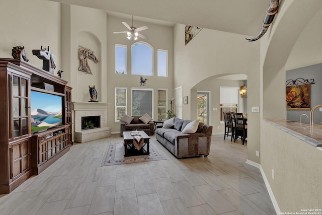 577 River Chase, New Braunfels, TX 78132 - living area with a ceiling fan, a towering ceiling, arched walkways, and a fireplace