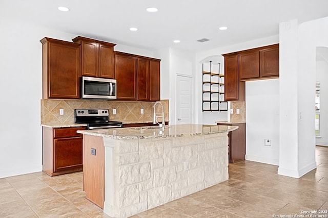 105 Highland Pl, Cibolo, TX 78108 - kitchen featuring appliances with stainless steel finishes, light stone counters, a center island with sink, backsplash, and recessed lighting
