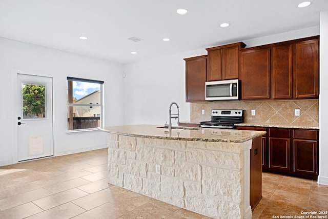 105 Highland Pl, Cibolo, TX 78108 - kitchen featuring stainless steel microwave, electric range oven, a kitchen island with sink, tasteful backsplash, and light stone counters