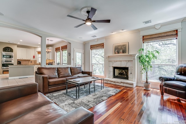 13610 Pearlstone, San Antonio, TX 78232 - living area featuring ceiling fan, arched walkways, a fireplace with raised hearth, ornamental molding, and light wood finished floors