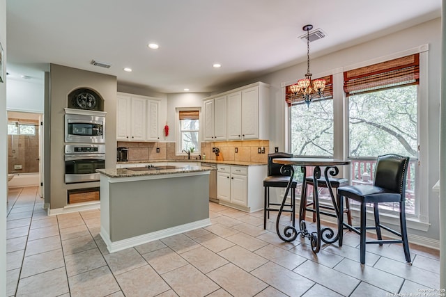13610 Pearlstone, San Antonio, TX 78232 - kitchen featuring stainless steel appliances, a chandelier, tasteful backsplash, a kitchen island, and white cabinetry