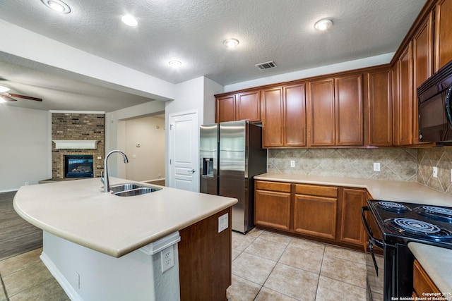 25547 Veining, San Antonio, TX 78261 - kitchen with black appliances, decorative backsplash, a brick fireplace, open floor plan, and a textured ceiling