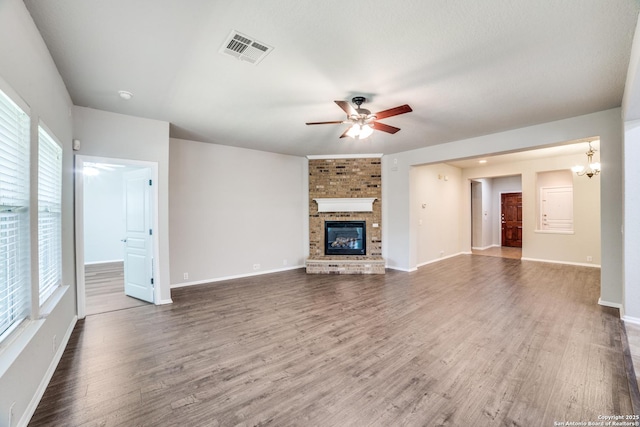 25547 Veining, San Antonio, TX 78261 - unfurnished living room featuring a ceiling fan, a brick fireplace, wood finished floors, and a chandelier