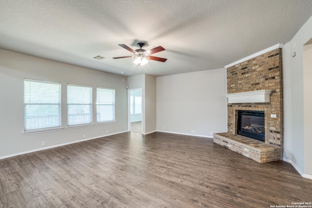 25547 Veining, San Antonio, TX 78261 - unfurnished living room featuring ceiling fan, dark wood-style flooring, a fireplace, and a textured ceiling
