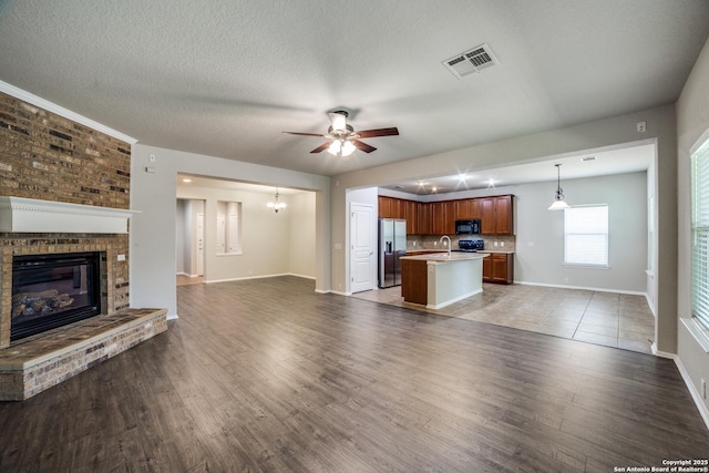 25547 Veining, San Antonio, TX 78261 - unfurnished living room featuring a fireplace, a ceiling fan, light wood-type flooring, and a textured ceiling