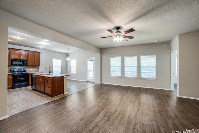 25547 Veining, San Antonio, TX 78261 - kitchen featuring black appliances, wood finished floors, open floor plan, light countertops, and brown cabinets