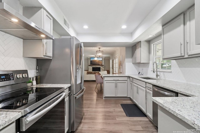 1710 Searcy, San Antonio, TX 78232 - kitchen with stainless steel appliances, wall chimney range hood, wood finished floors, recessed lighting, and a chandelier