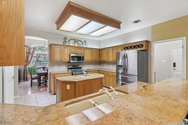 127 Sunflower Ln, San Antonio, TX 78213 - kitchen featuring stainless steel appliances, an island with sink, backsplash, light tile patterned floors, and light stone countertops