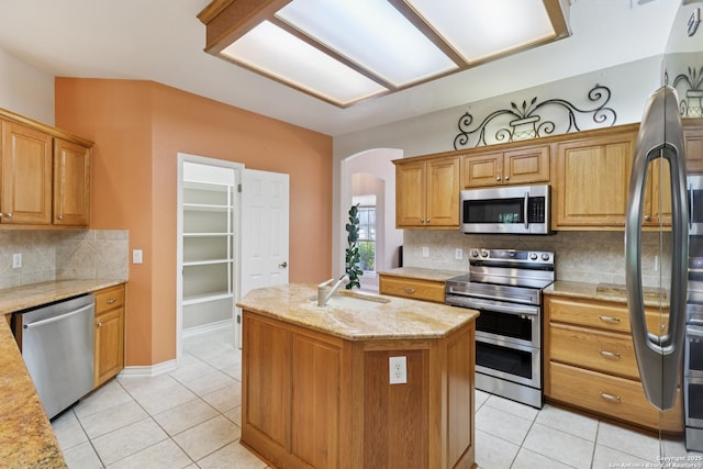 127 Sunflower Ln, San Antonio, TX 78213 - kitchen featuring stainless steel appliances, arched walkways, light tile patterned floors, backsplash, and a kitchen island with sink