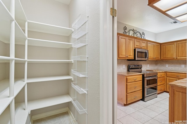 127 Sunflower Ln, San Antonio, TX 78213 - kitchen featuring appliances with stainless steel finishes, backsplash, light tile patterned floors, and brown cabinets
