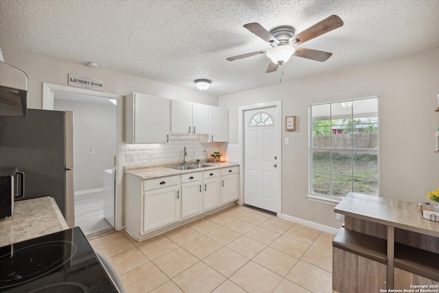 5311 Light House, San Antonio, TX 78242 - kitchen with freestanding refrigerator, light countertops, ceiling fan, white cabinets, and decorative backsplash