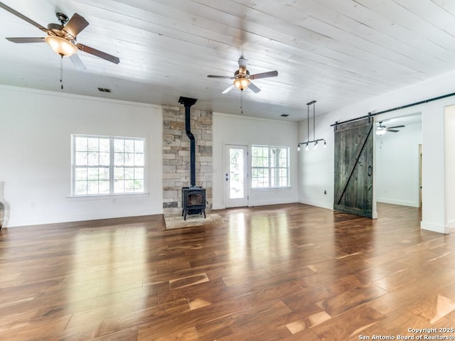 2521 Bay Hl, Bulverde, TX 78163 - unfurnished living room with a barn door, a ceiling fan, a wood stove, wood finished floors, and crown molding