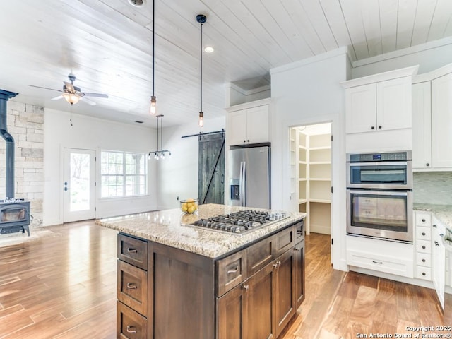 2521 Bay Hl, Bulverde, TX 78163 - kitchen featuring appliances with stainless steel finishes, wooden ceiling, a wood stove, ceiling fan, and white cabinets