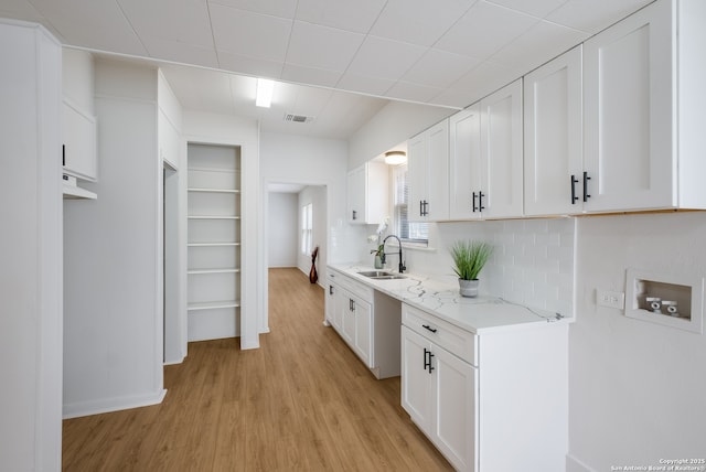 1002 Aganier, San Antonio, TX 78212 - kitchen with light wood-style flooring, white cabinets, backsplash, and light stone counters