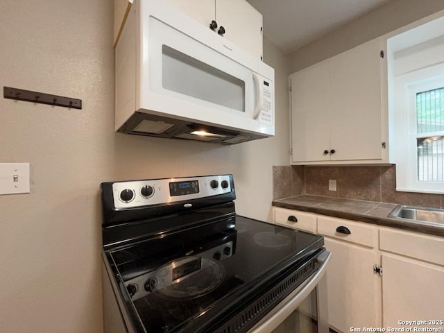 443 Seele, New Braunfels, TX 78130 - kitchen featuring white microwave, stainless steel electric range oven, white cabinets, decorative backsplash, and tile countertops