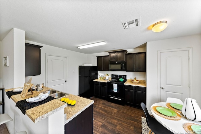 3827 Southton Vw, San Antonio, TX 78222 - kitchen featuring black appliances, a peninsula, dark wood-style flooring, dark brown cabinets, and a textured ceiling
