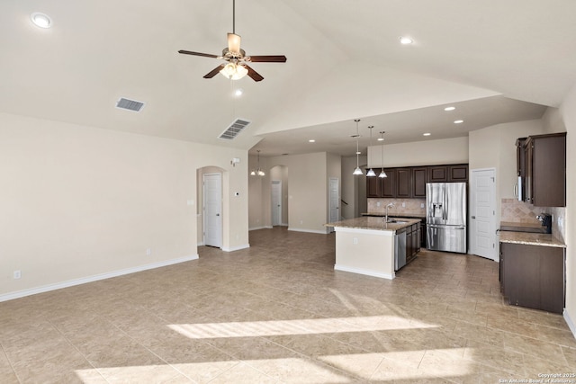 601 Saddle Villa, Cibolo, TX 78108 - kitchen featuring stainless steel appliances, open floor plan, arched walkways, a kitchen island with sink, and dark brown cabinetry