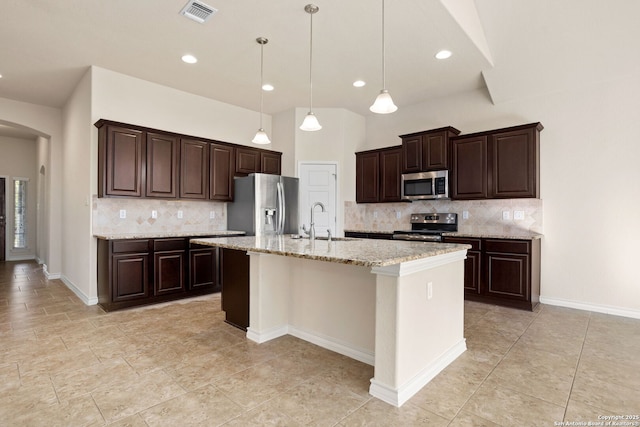 601 Saddle Villa, Cibolo, TX 78108 - kitchen featuring stainless steel appliances, arched walkways, decorative backsplash, dark brown cabinets, and a kitchen island with sink