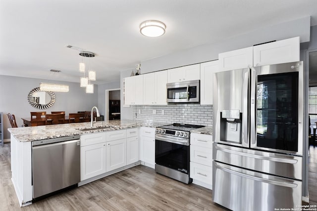 1654 Rob Roy, San Antonio, TX 78251 - kitchen with stainless steel appliances, a peninsula, white cabinetry, backsplash, and light wood finished floors