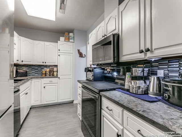1 Towers Park Unit 211, San Antonio, TX 78209 - kitchen with electric range, stainless steel microwave, tasteful backsplash, white cabinetry, and dark countertops