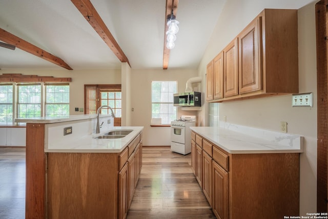 9071 Fm 725, Mcqueeney, TX 78123 - kitchen with white range with gas cooktop, stainless steel microwave, beamed ceiling, light wood-type flooring, and a center island with sink