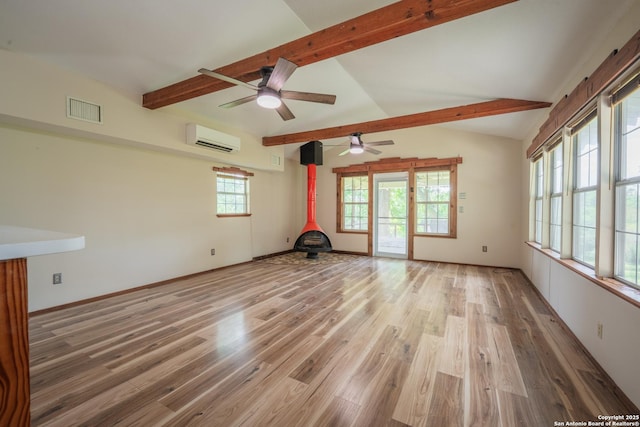 9071 Fm 725, Mcqueeney, TX 78123 - unfurnished living room featuring a wall unit AC, a wood stove, a ceiling fan, and light wood-style floors